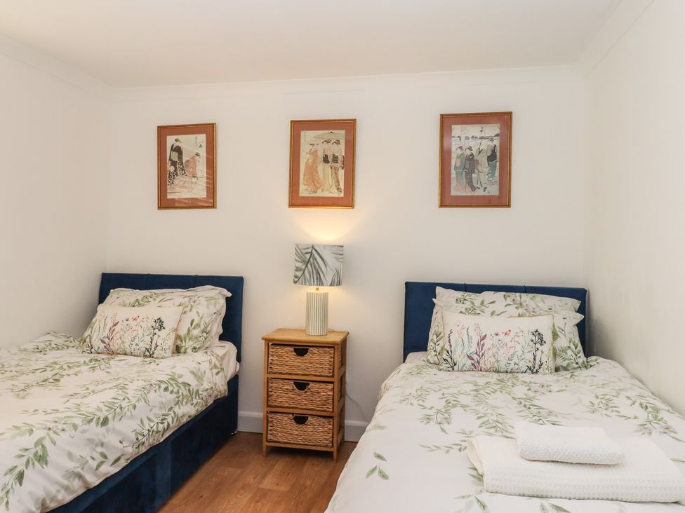 A bedroom with two beds and artwork on the wall at Marina Court Apartment in Torquay