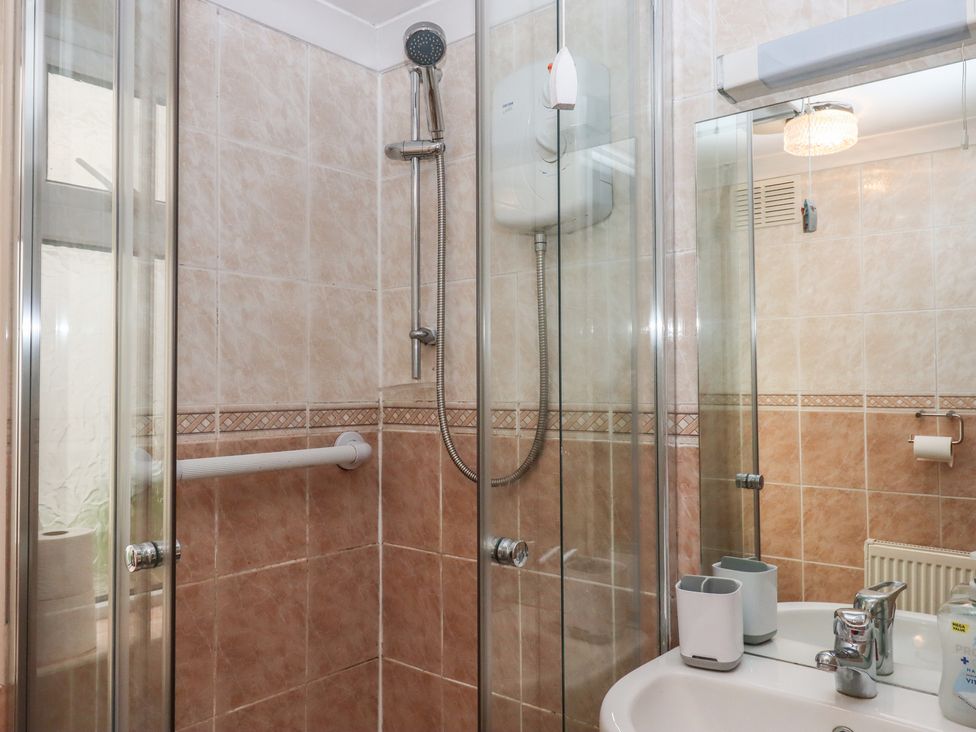 A bathroom with a shower, sink, and toiletries at Marina Court Apartment in Torquay