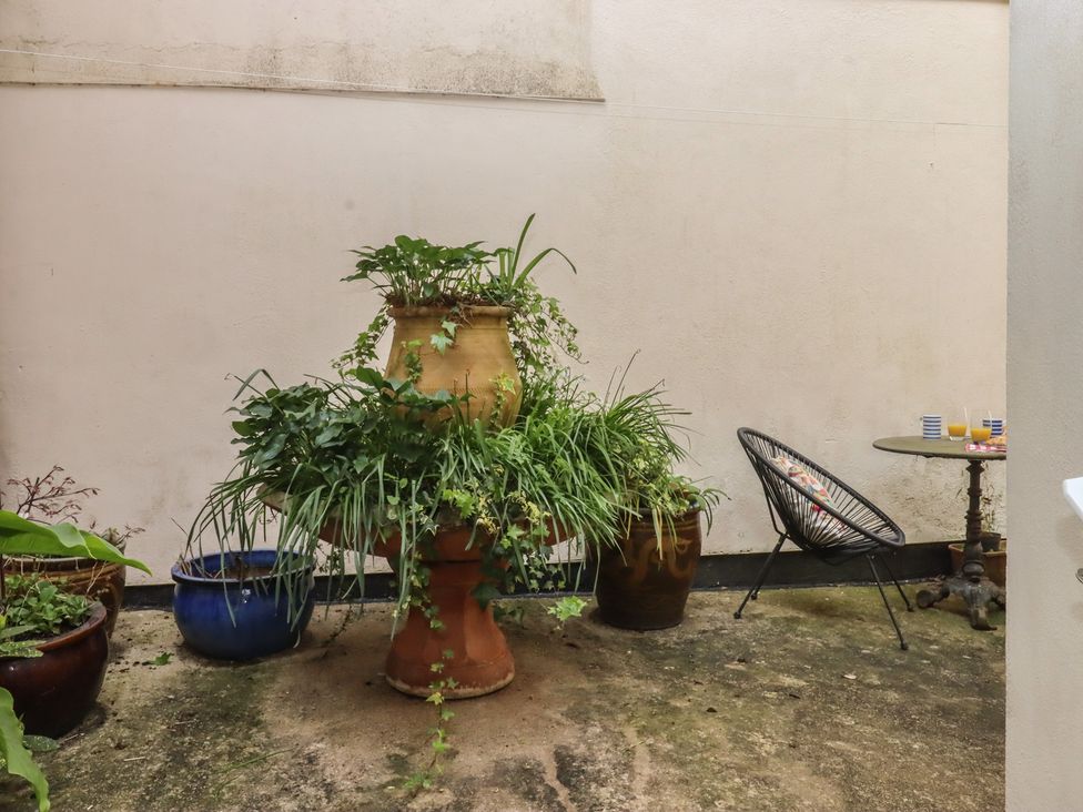 A garden featuring a potted plant and a table with a chair at Marina Court Apartment in Torquay