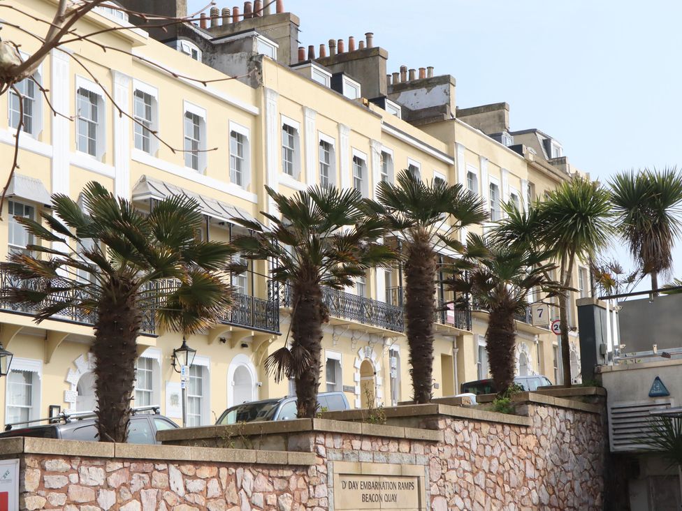 A row of buildings with palm trees and cars at Marina Court Apartment in Torquay