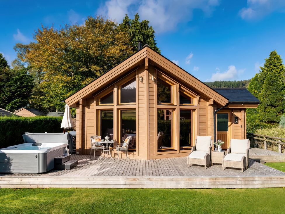An outdoor setting with a hot tub and seating area at Cwtch Log Cabin in Llandrillo