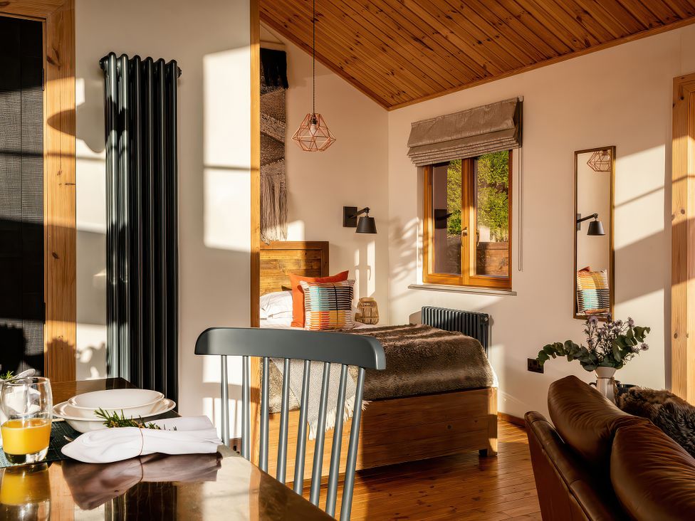 A bedroom with a bed and window at Cwtch Log Cabin Llandrillo