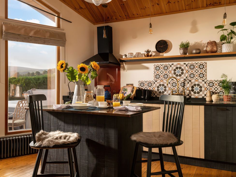 A kitchen with a countertop and stools at Cwtch Log Cabin Llandrillo