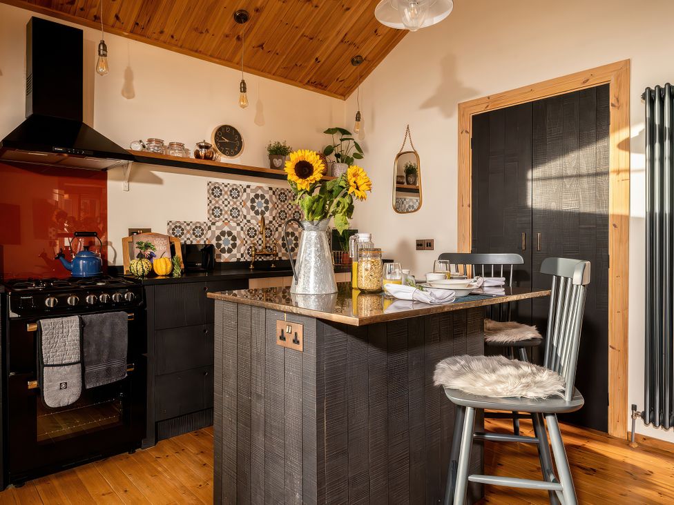 A kitchen with a stove and counter adorned with sunflowers at Cwtch Log Cabin Llandrillo