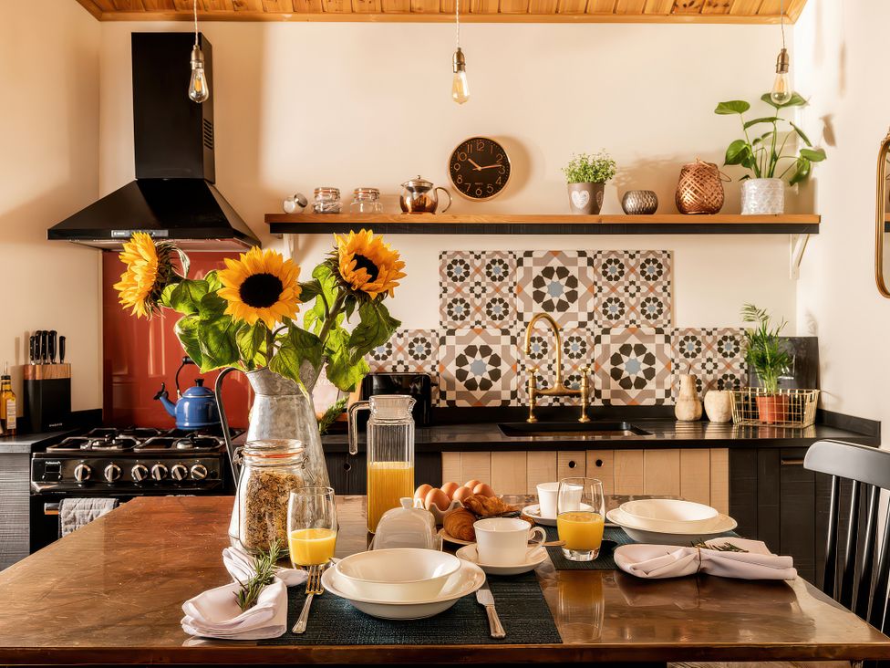 A kitchen with a sink, stove, and breakfast items at Cwtch Log Cabin in Llandrillo