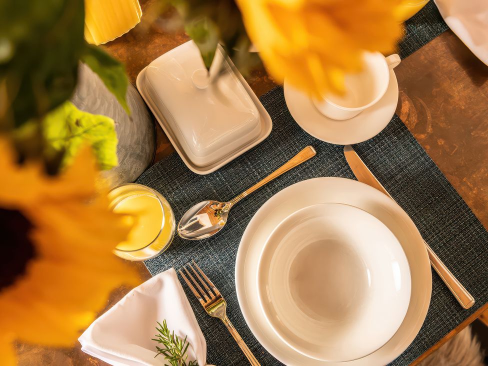 A dining table set with plates and cutlery at Cwtch Log Cabin in Llandrillo