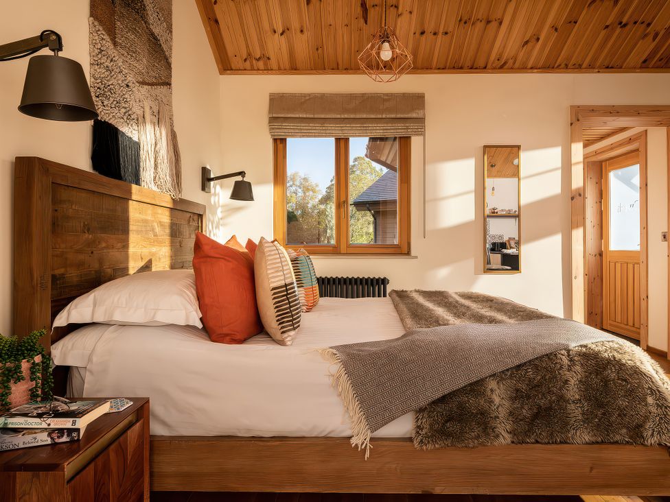 A bedroom with a bed and window at Cwtch Log Cabin in Llandrillo