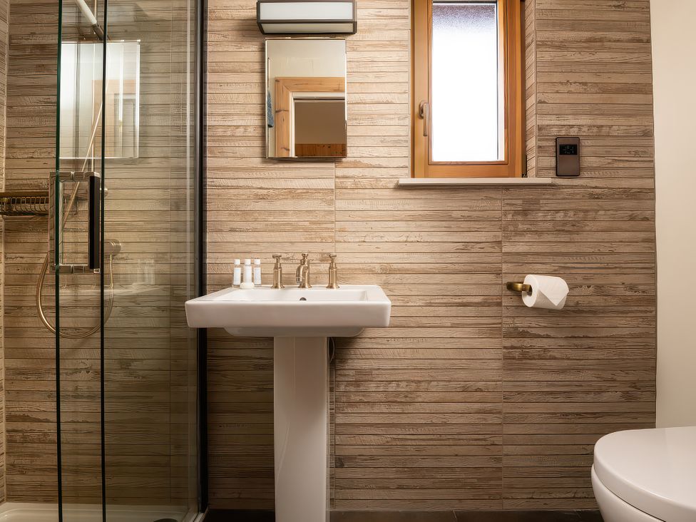 A bathroom with a shower, sink, and toilet at Cwtch Log Cabin in Llandrillo