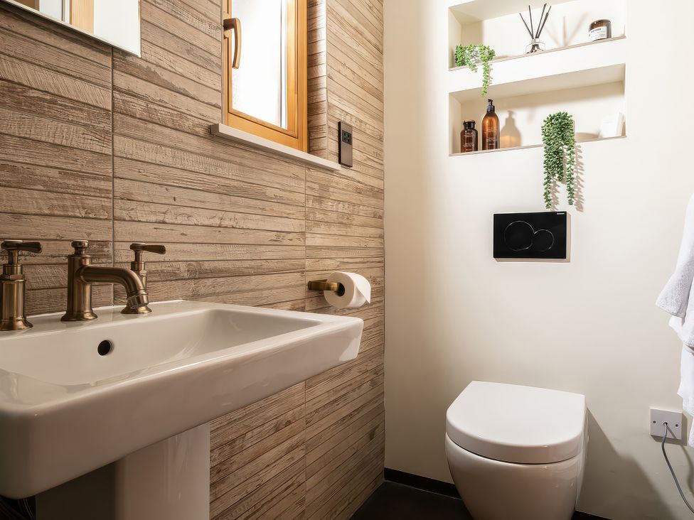 A bathroom with a sink and toilet at Cwtch Log Cabin Llandrillo