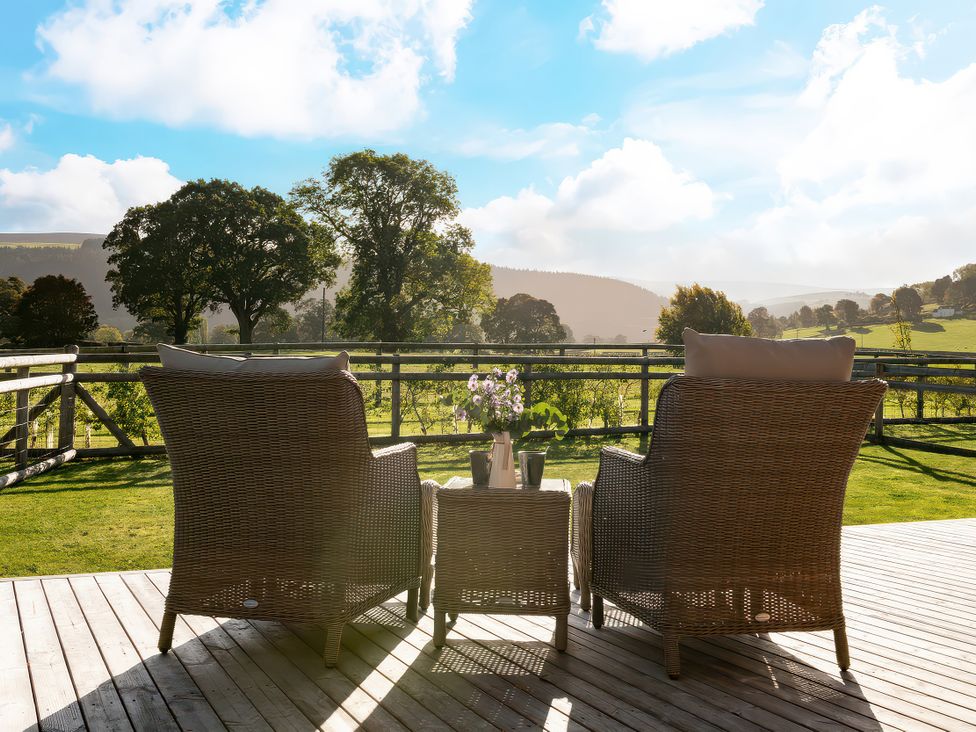 An outdoor patio with chairs and a table at Cwtch Log Cabin Llandrillo