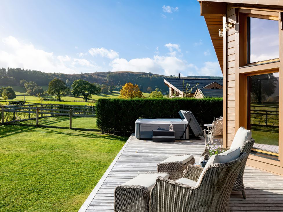 An outdoor area with a spa and deck chairs at Cwtch Log Cabin in Llandrillo