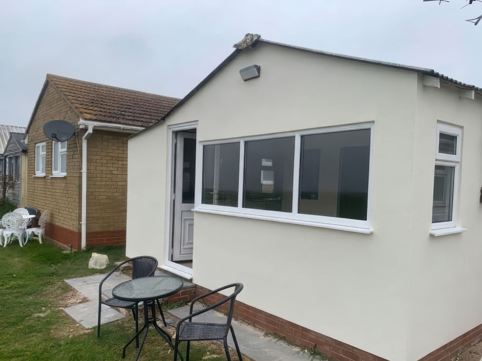 An exterior view of a house with a table and chairs at Watersmeet - 85 @ Park Avenue Holiday Village Leysdown-On-Sea, Kent