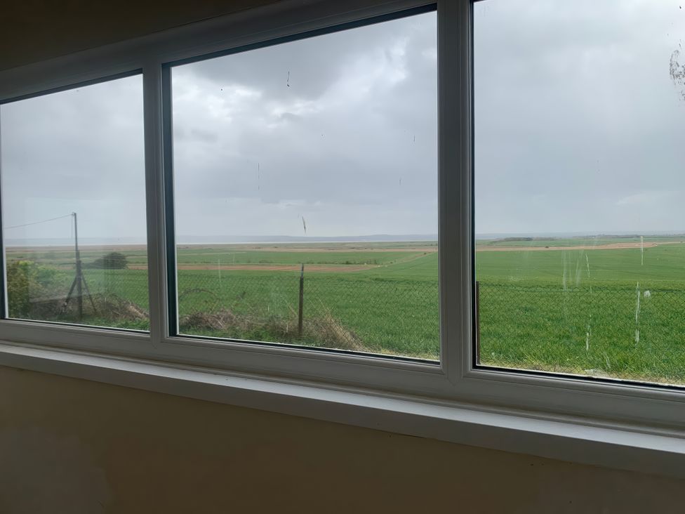 A view from a window showing green fields and cloudy sky at Watersmeet - 85 @ Park Avenue Holiday Village, Leysdown-On-Sea, Kent