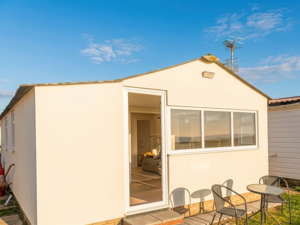 An exterior view of a house with a patio table and chairs at Watersmeet - 85 @ Park Avenue Holiday Village, Leysdown-On-Sea, Kent