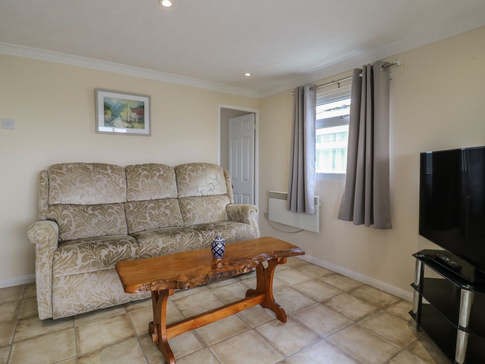 A living room with a sofa and a wooden table at Watersmeet - 85 @ Park Avenue Holiday Village, Leysdown-On-Sea, Kent