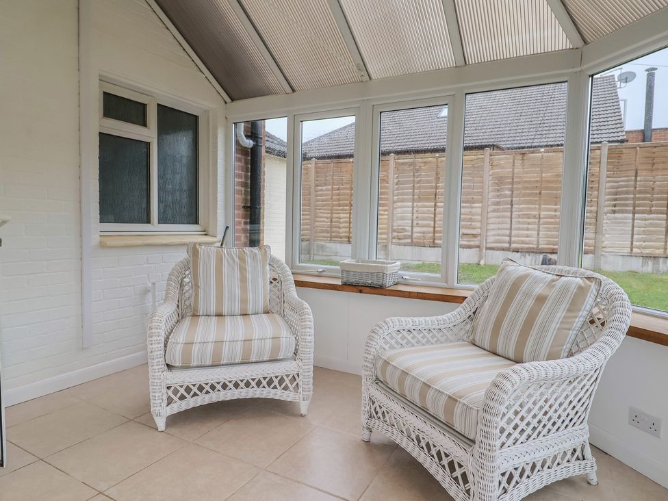 A conservatory with two rattan chairs and a table at 2 North Road, Maiden Newton, Dorset