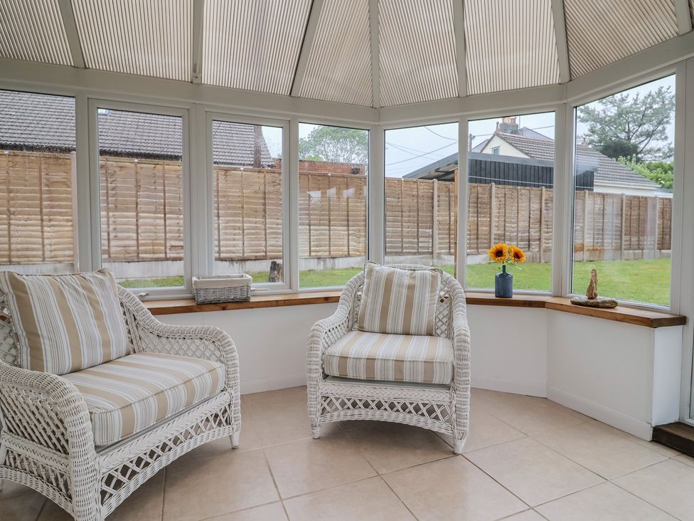 A conservatory with armchairs and a vase of sunflowers at 2 North Road Maiden Newton, Dorset