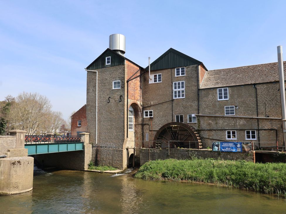 A water wheel and building next to a river at 2 North Road, Maiden Newton, Dorset