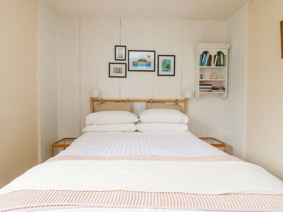 A bedroom with a bed and shelves at Wootton Gray in Penzance