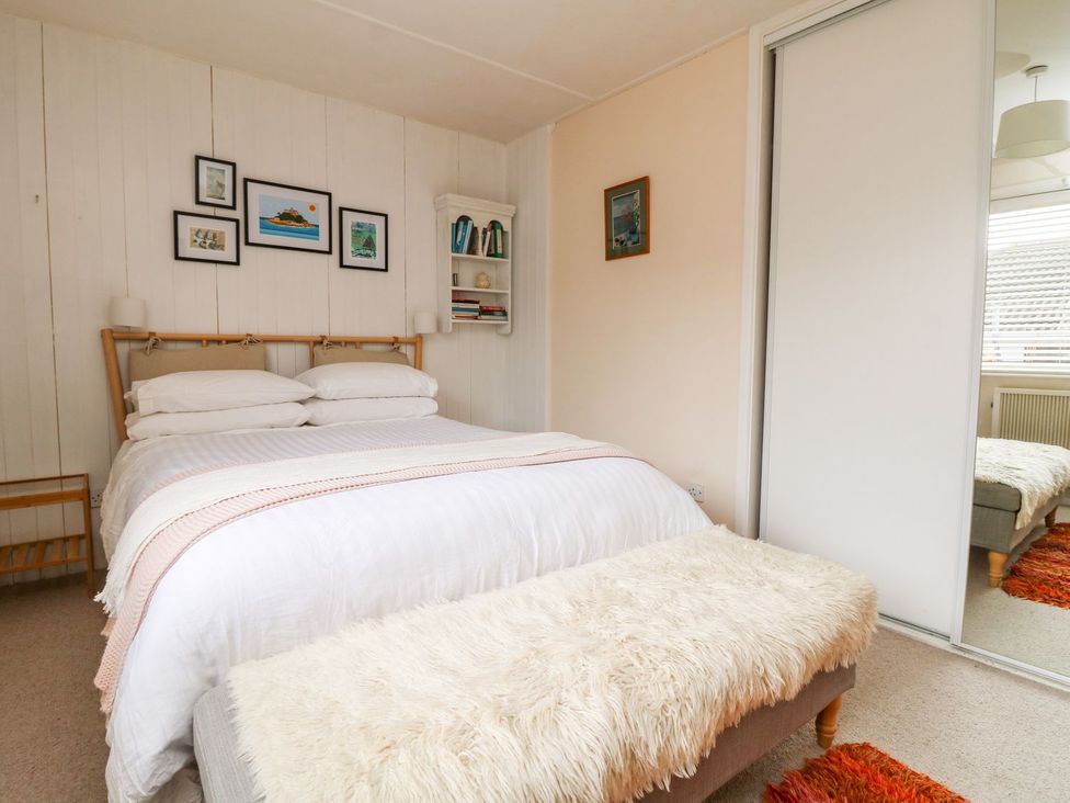 A bedroom with a bed and shelves at Wootton Gray in Penzance