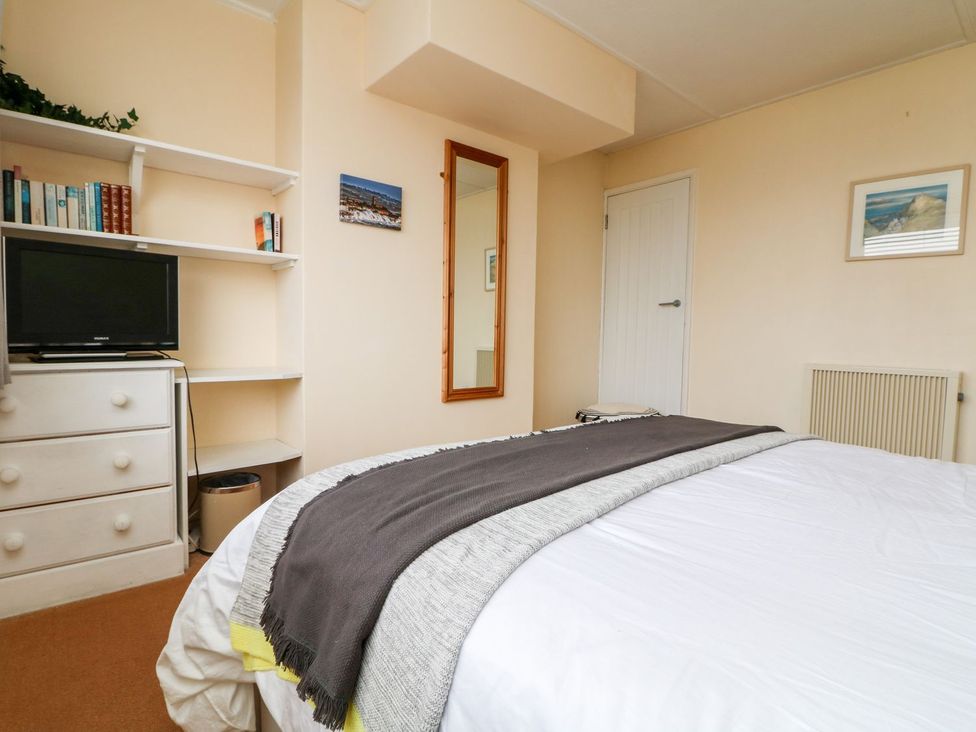 A bedroom with a bed and shelves at Wootton Gray in Penzance