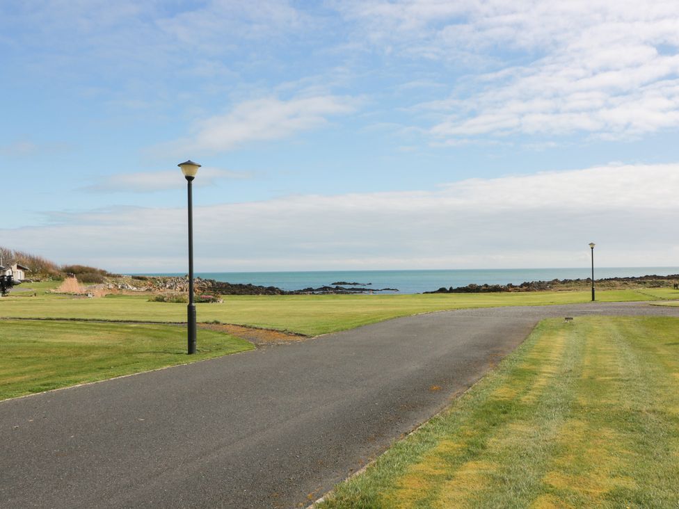 A road leading to the sea with grass and a lamp post at 15 Laigh Isle
