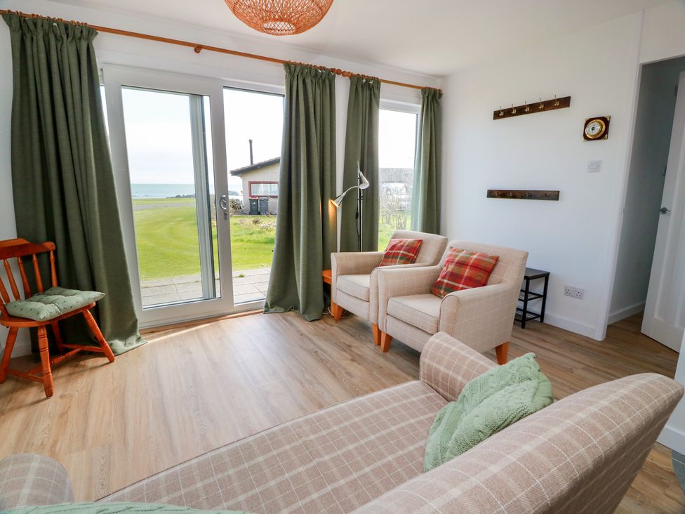 A living room with chairs and a sofa overlooking a view at 15 Laigh Isle 