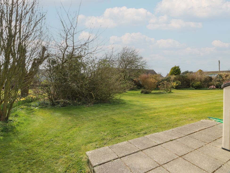 A garden with grass, trees, and a patio at 15 Laigh Isle 