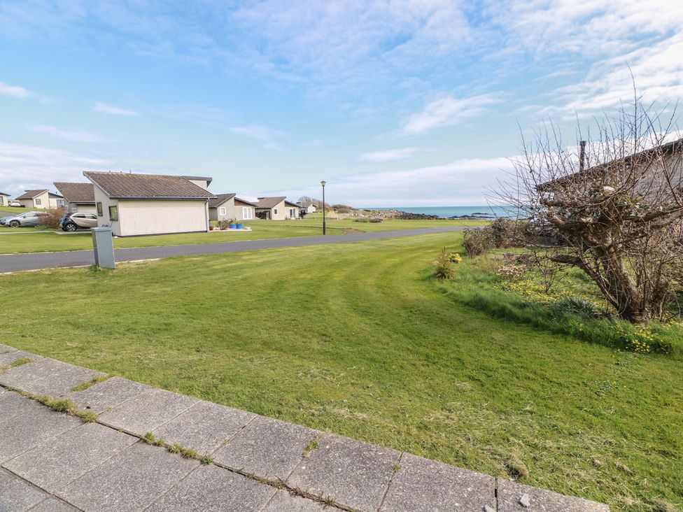A view of houses and sea from a grassy area at 15 Laigh Isle