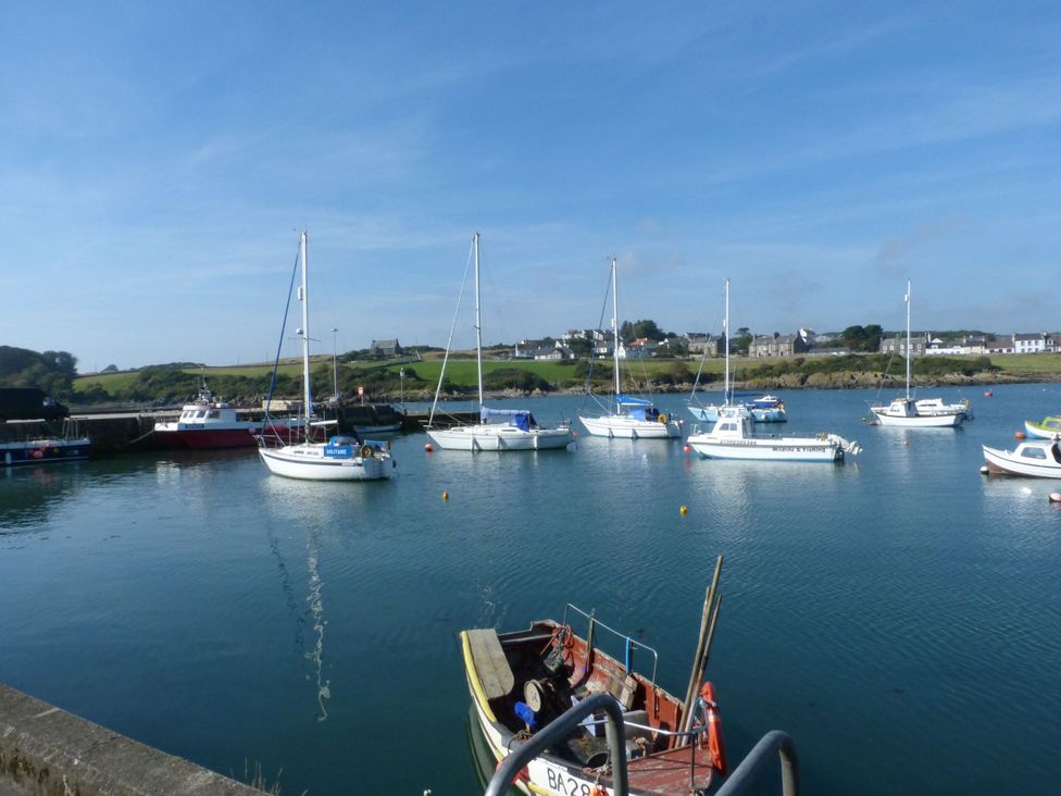 Boats moored in a harbor with clear water at 15 Laigh Isle