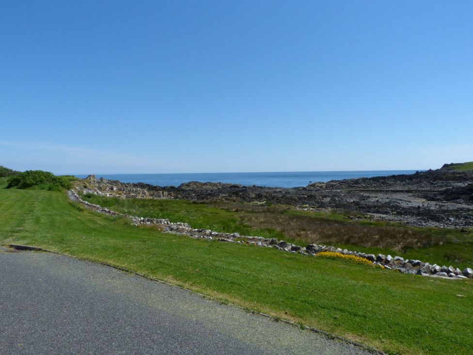 A view of the ocean with grassy area and rocky shore at 15 Laigh Isle
