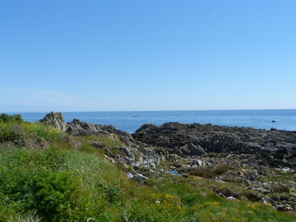 A view of the sea with rocks and grass at 15 Laigh Isle