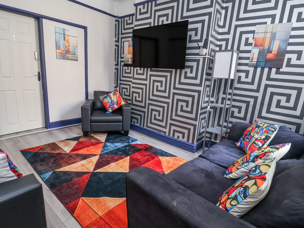 A living room with a TV and colorful rug at Ince Lodge Liverpool