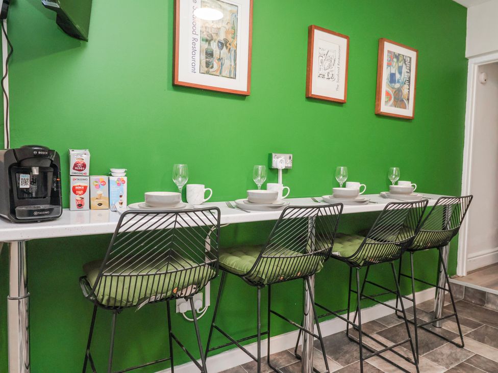 A kitchen with bar stools and coffee machine at Ince Lodge Liverpool