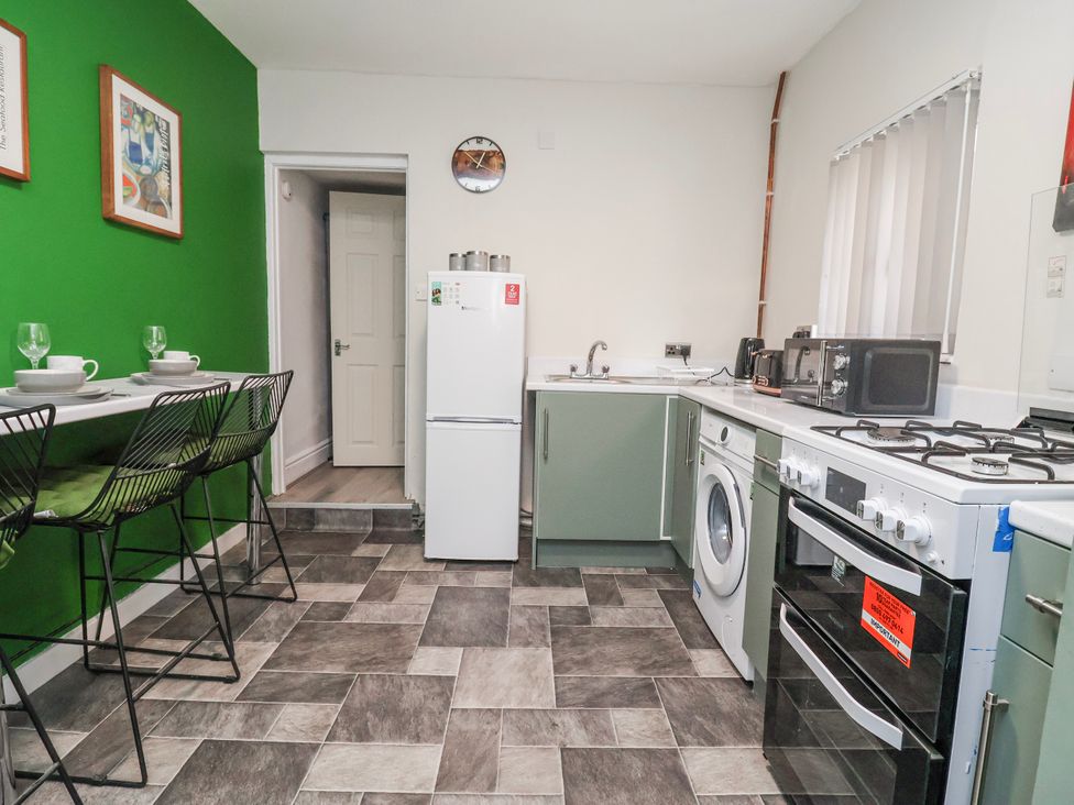 A kitchen with appliances and bar stools at Ince Lodge in Liverpool