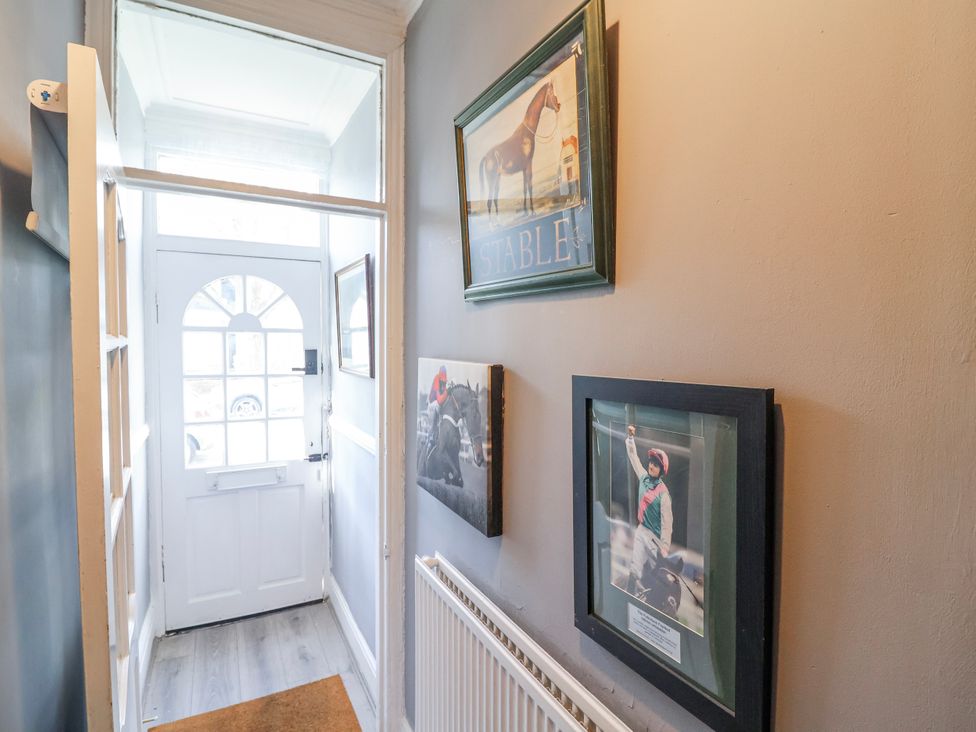 A hallway with a door, pictures on the wall, and a radiator at Ince Lodge Liverpool
