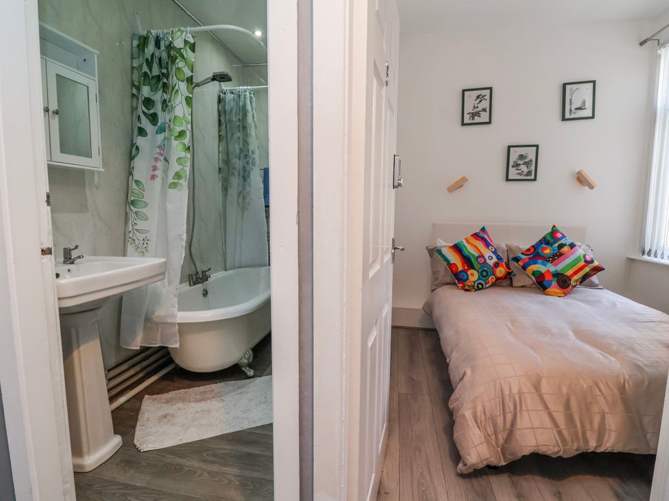 A bathroom with a bathtub and sink next to a bedroom with a bed at Ince Lodge in Liverpool