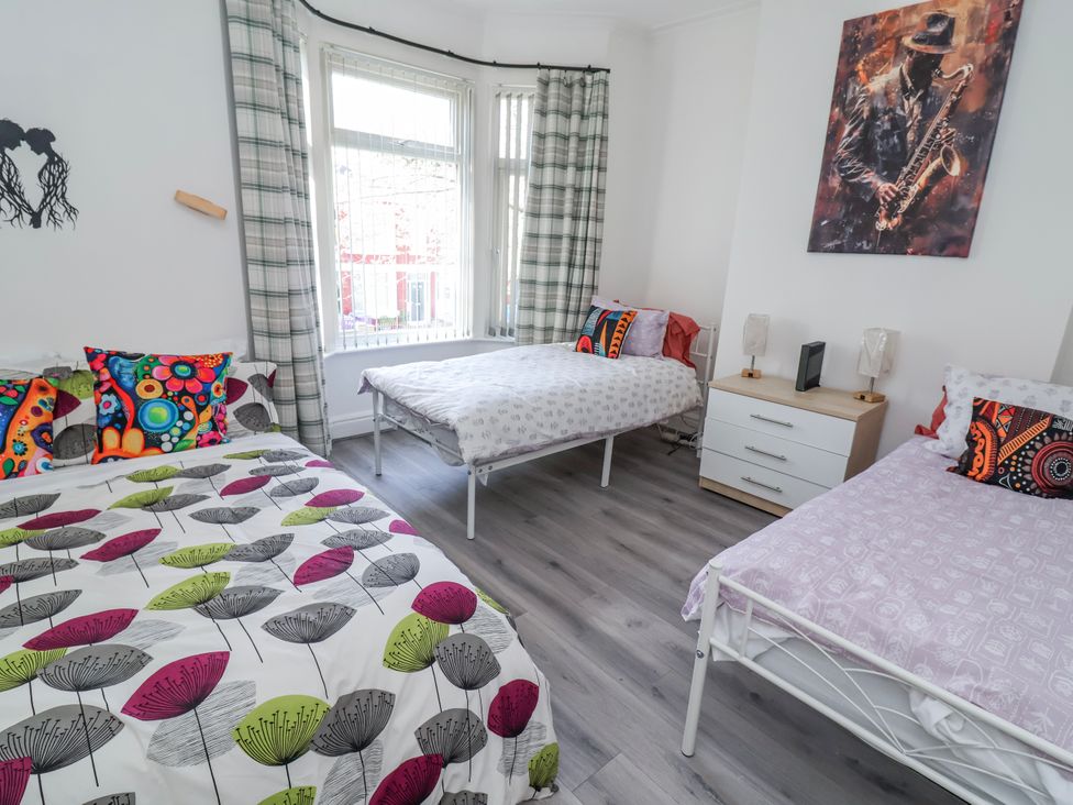 A bedroom with three beds and a bedside table at Ince Lodge in Liverpool