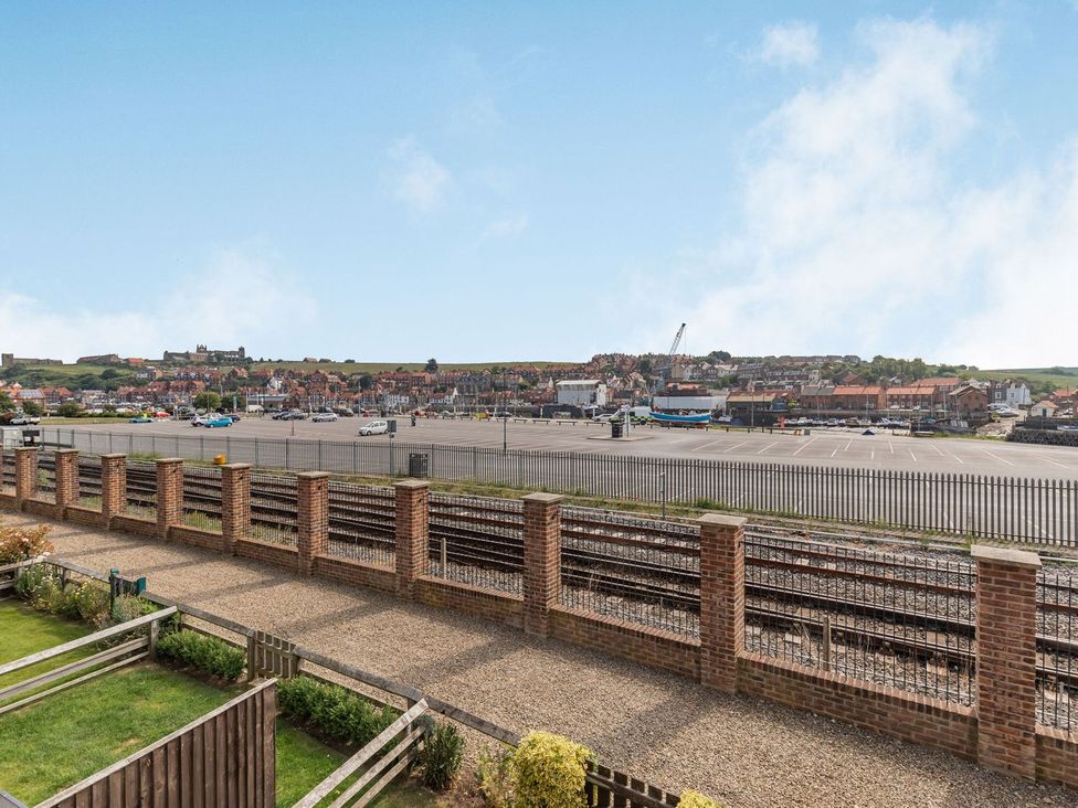 A view of a parking area and buildings from a property with a fence at Rails End