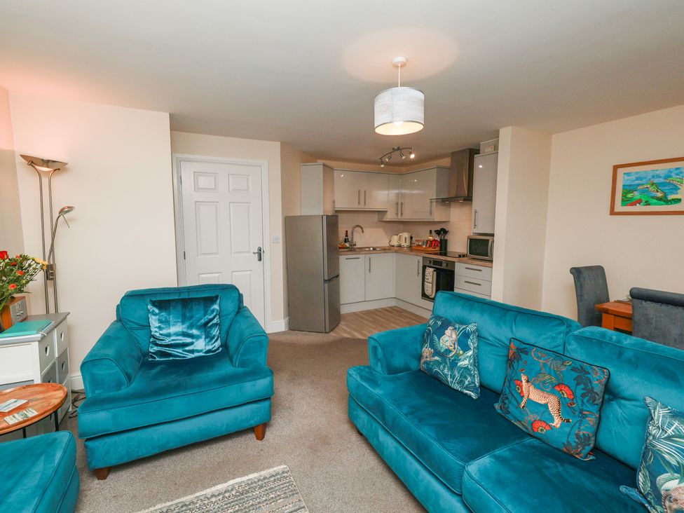 A living room with a sofa and kitchen area at Rails End in Whitby