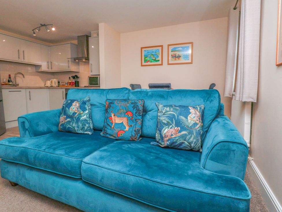 A living room with a blue sofa and kitchen area at Rails End in Whitby