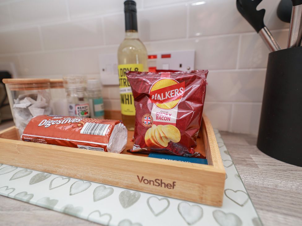 A kitchen with a bamboo tray containing biscuits and crisps at Rails End in Whitby