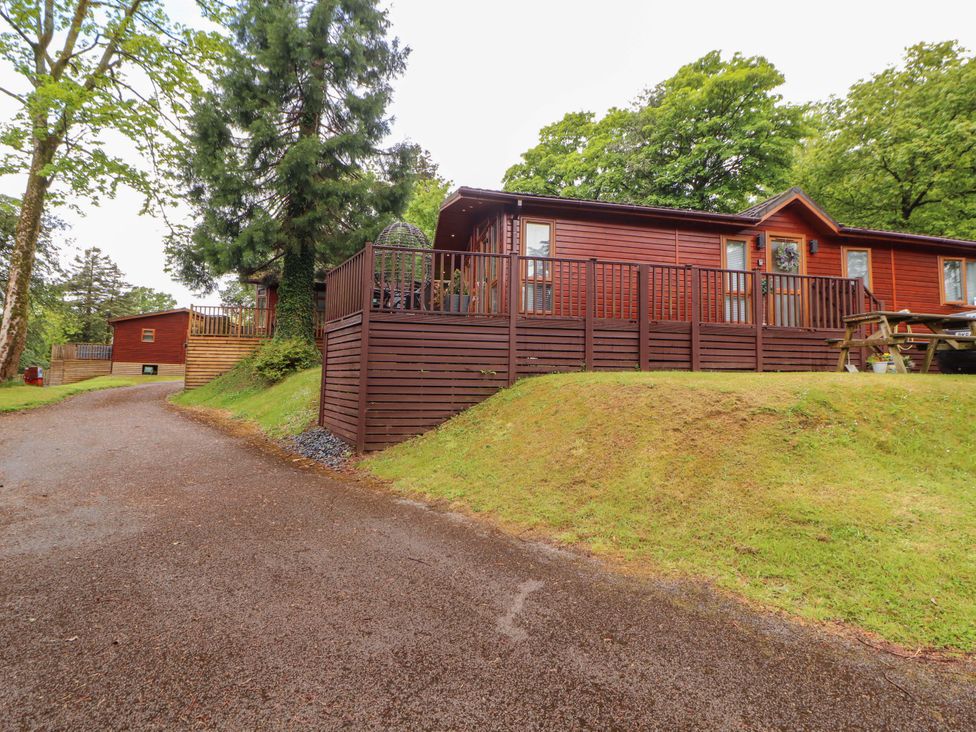 A wooden lodge with a deck and seating in Bowness-On-Windermere