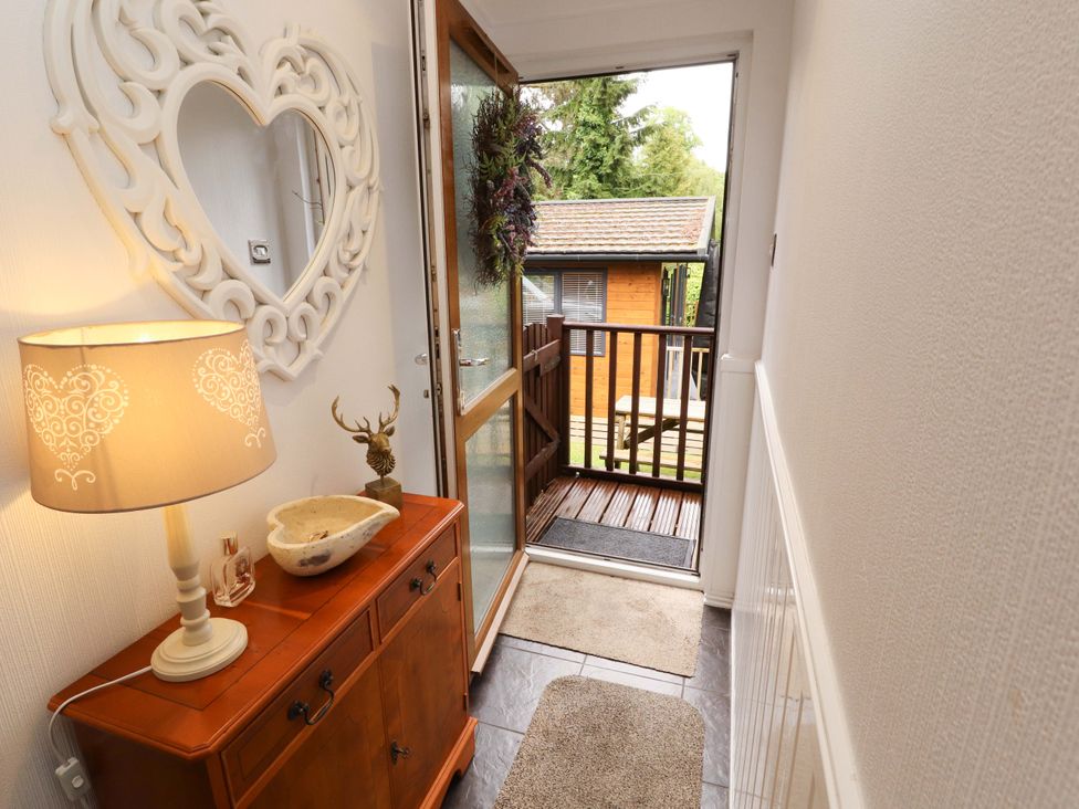 An entrance hall with a table and lamp at Jodene Lodge, Redwood 2, Bowness-On-Windermere