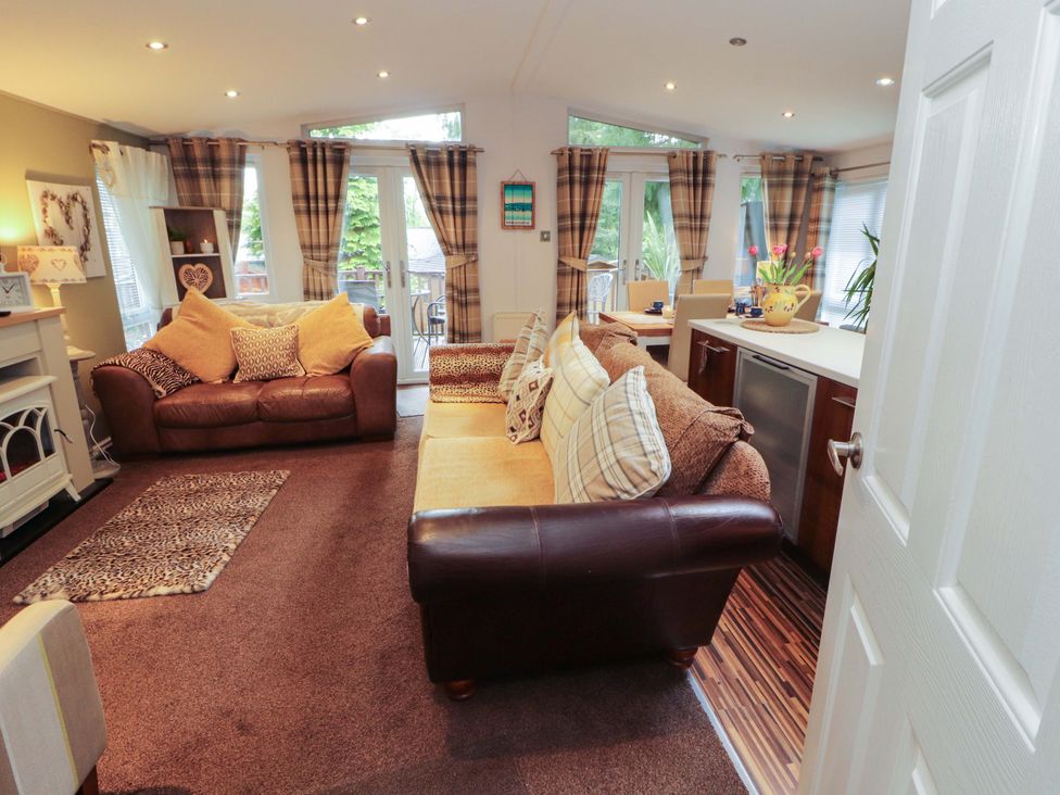 A living room with a sofa and dining area at Jodene Lodge, Redwood 2 Bowness-On-Windermere