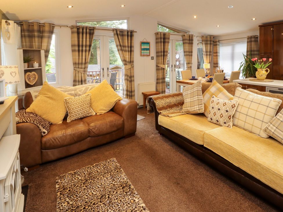 A living room with a sofa and a dining table at Jodene Lodge, Redwood 2 Bowness-On-Windermere