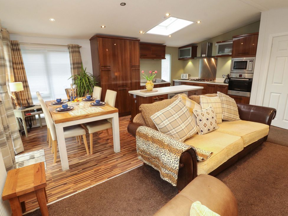 A kitchen and dining area with a table and sofa at Jodene Lodge, Redwood 2 Bowness-On-Windermere