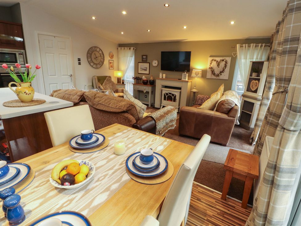 A dining area and living room with couch and table at Jodene Lodge, Redwood 2 Bowness-On-Windermere