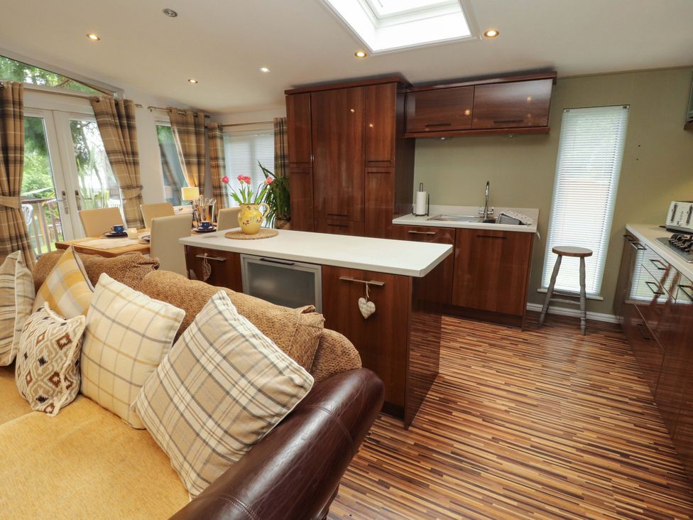 A kitchen with a counter, stools, and cabinets at Jodene Lodge, Redwood 2 Bowness-On-Windermere