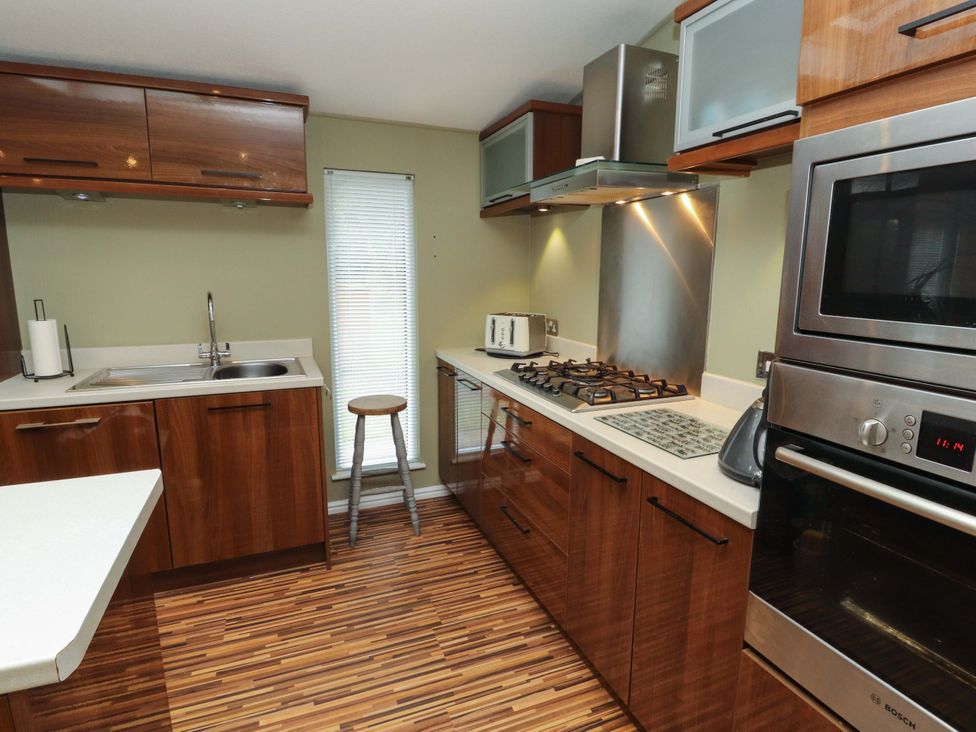 A kitchen with wooden cabinets and appliances at Jodene Lodge, Redwood 2 Bowness-On-Windermere